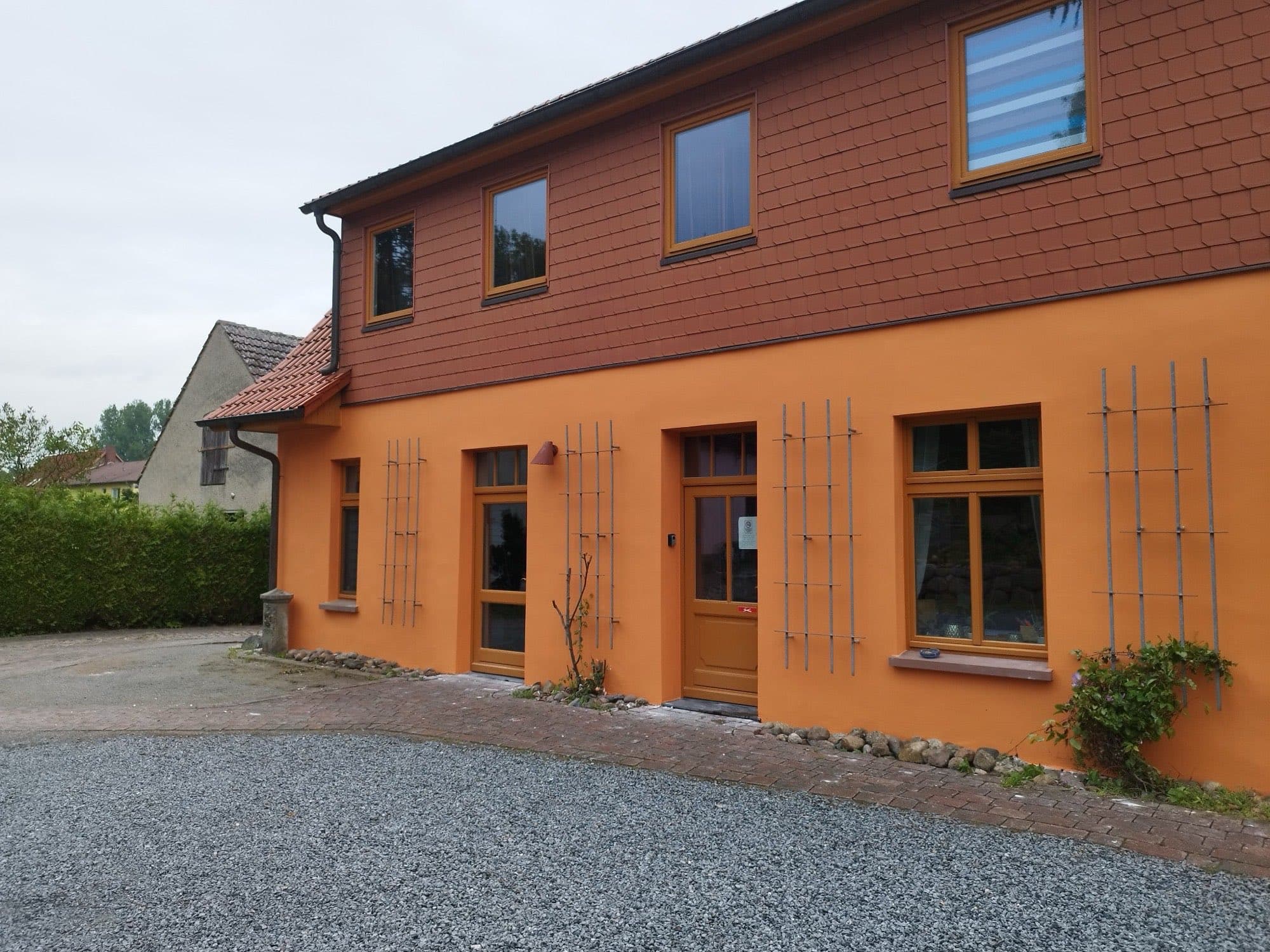 Frisch gestrichene orangefarbene Altbaufassade mit weißen Fensterfaschen